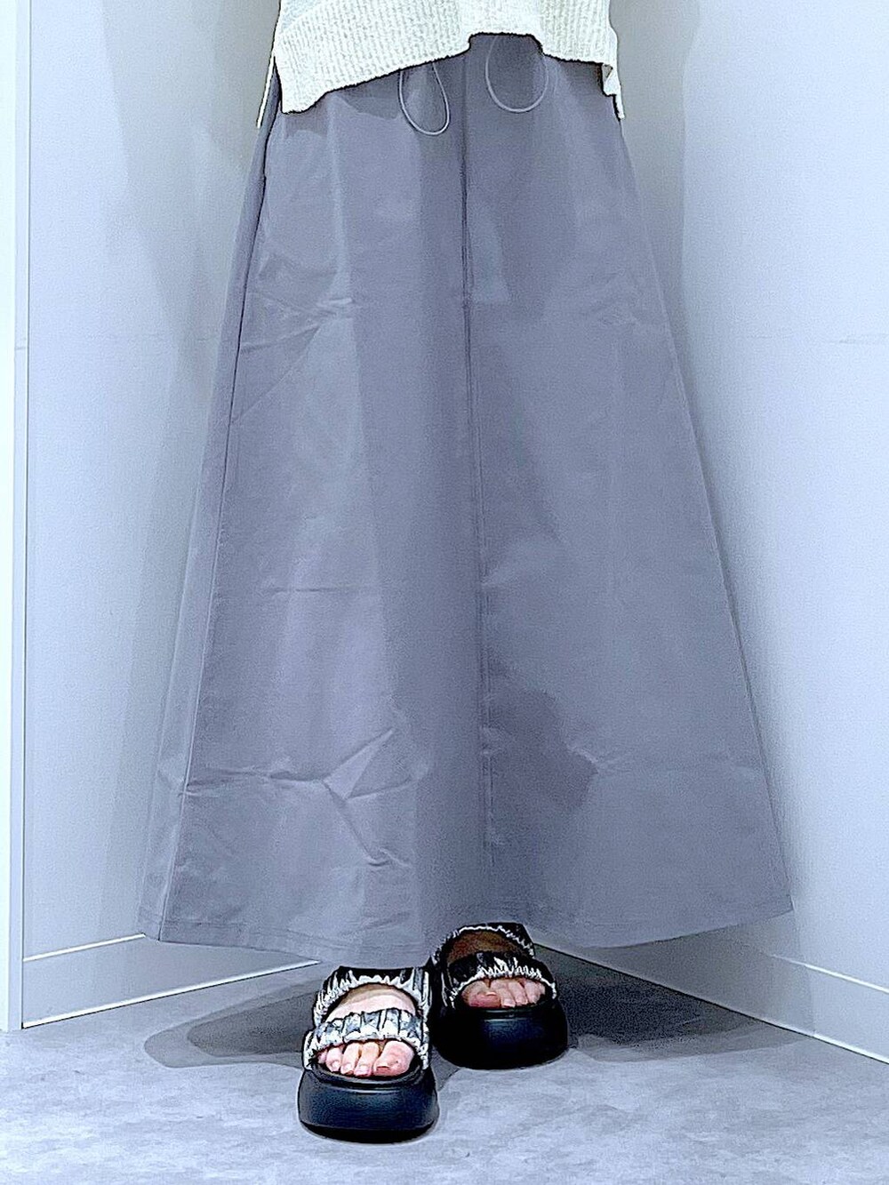 シルバー系のサンダル、グレー系のスカート、ホワイト系のベストを着用したレディースの夏コーディネートの8枚目の写真