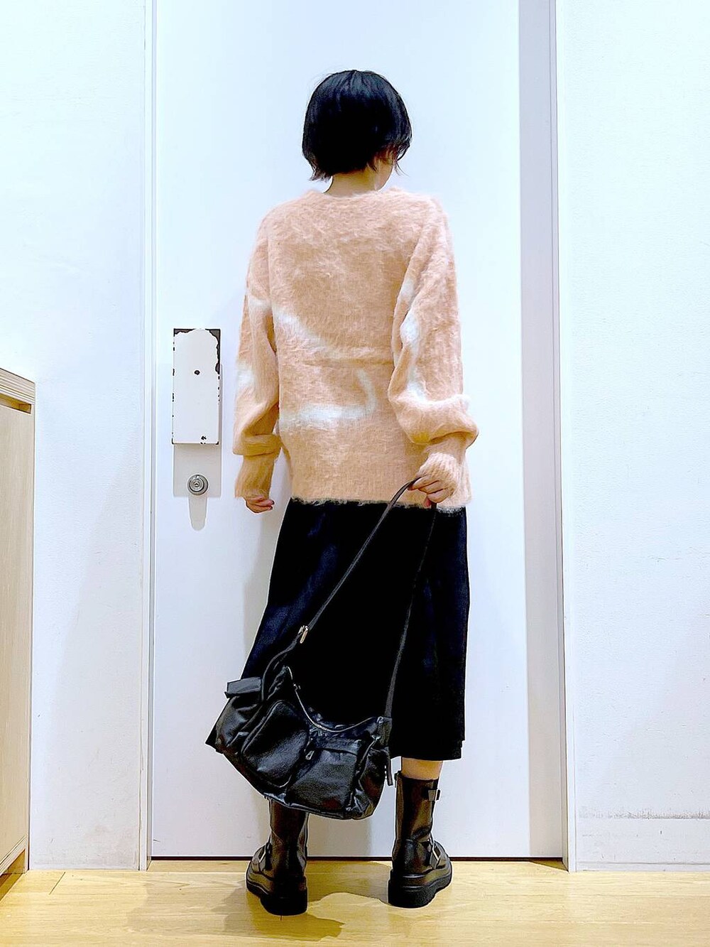 ピンク系のニット/セーター、ブラック系のブーツ、ブラック系のショルダーバッグを着用したレディースの秋コーディネートの5枚目の写真