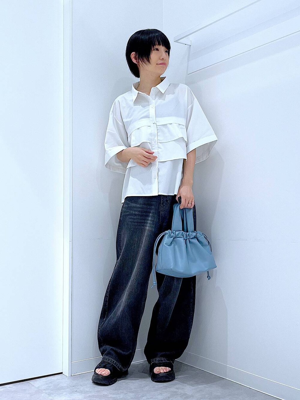ブラック系のデニムパンツ、ブラック系のスニーカー、ブルー系のショルダーバッグを着用したレディースの夏コーディネートの2枚目の写真