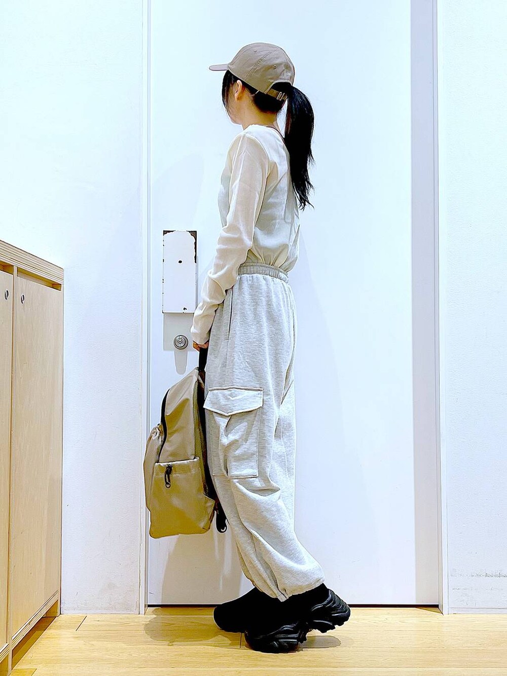 グレー系のスウェットパンツ、ベージュ系のバックパック/リュック、ブラック系のスニーカーを着用したレディースの春コーディネートの3枚目の写真