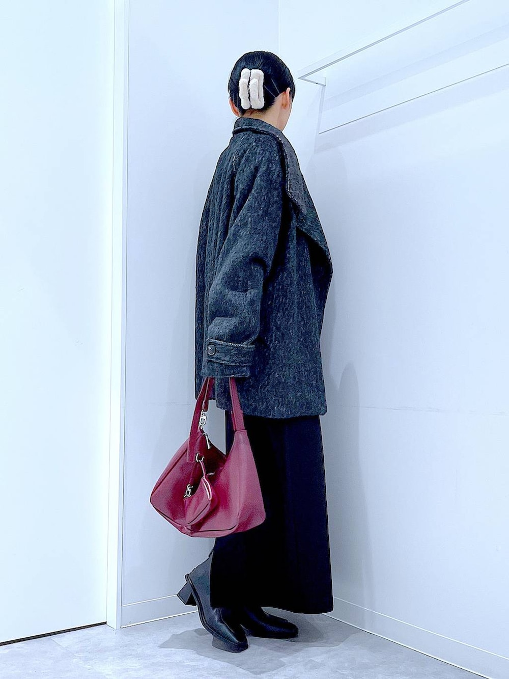 ブラック系のスカート、ブラック系のステンカラーコート、ブラック系のブーツを着用したレディースの冬コーディネートの4枚目の写真