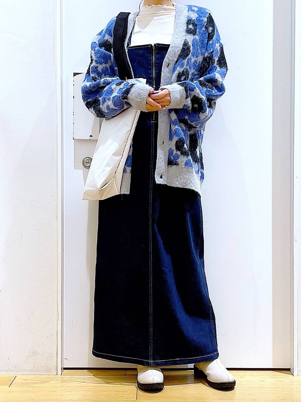 ブルー系のジャンパースカート、ホワイト系のTシャツ/カットソー、ベージュ系のブーツを着用したレディースの冬コーディネートの6枚目の写真