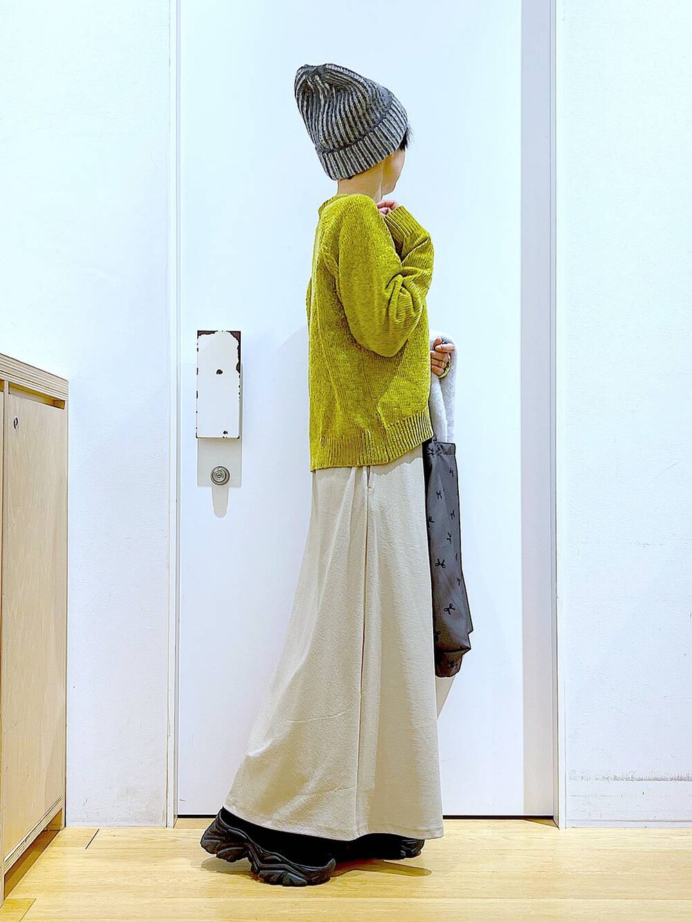 ブラック系のブーツ、その他のトートバッグ、グレー系のスカートを着用したレディースの冬コーディネートの4枚目の写真