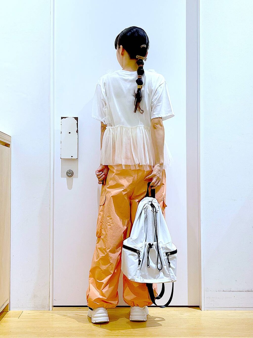 ホワイト系のスニーカー、ホワイト系のショルダーバッグ、オレンジ系のカーゴパンツを着用したレディースの夏コーディネートの5枚目の写真