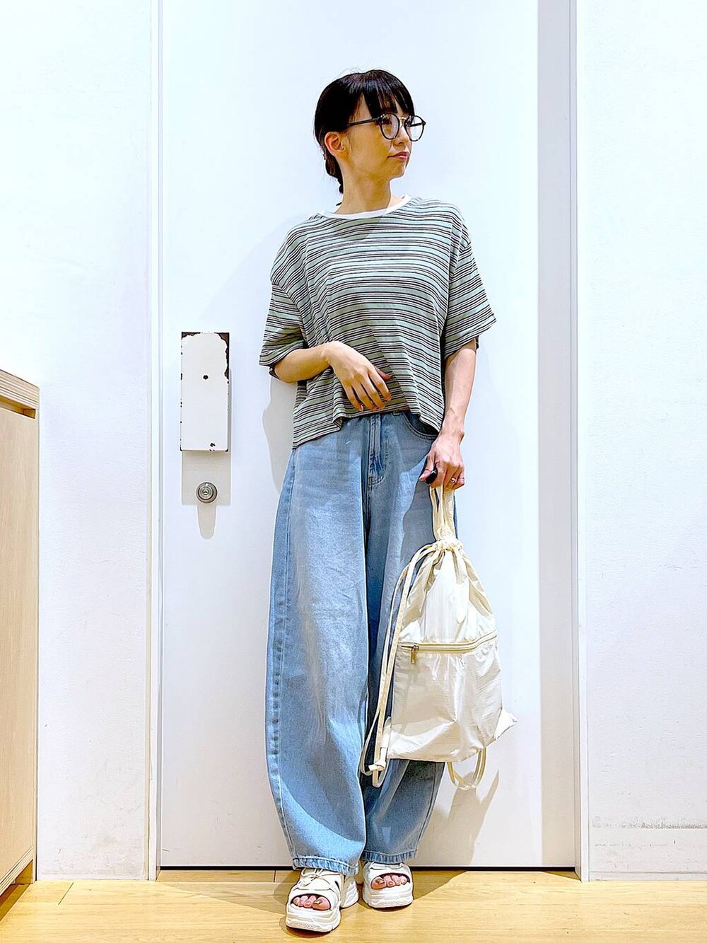 ホワイト系のバックパック/リュック、ホワイト系のサンダル、ブルー系のデニムパンツを着用したレディースの夏コーディネートの2枚目の写真