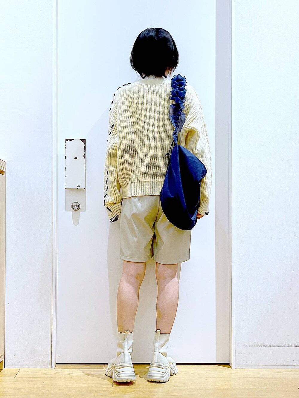 ベージュ系のニット/セーター、ブルー系のショルダーバッグ、ベージュ系のブーツを着用したレディースの冬コーディネートの5枚目の写真