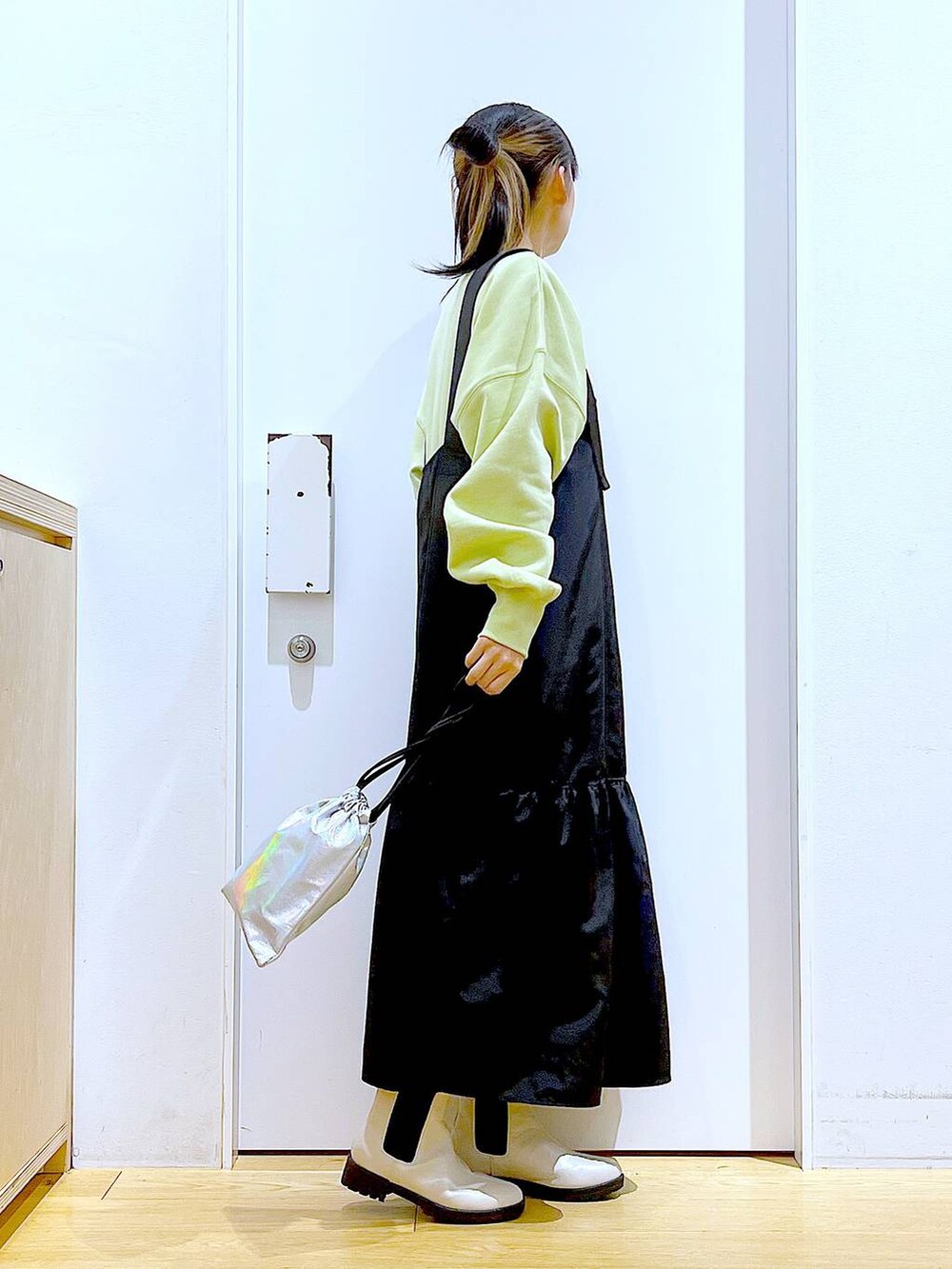 イエロー系のスウェット、ベージュ系のブーツ、その他のショルダーバッグを着用したレディースの冬コーディネートの4枚目の写真