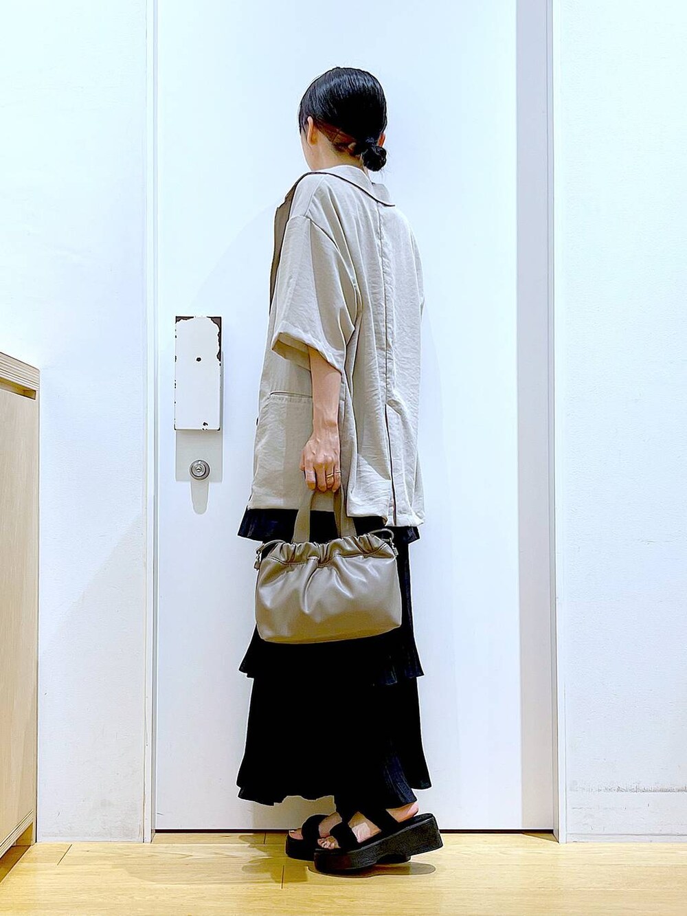 ブラック系のスカート、ブラック系のサンダル、ブラウン系のショルダーバッグを着用したレディースの夏コーディネートの3枚目の写真