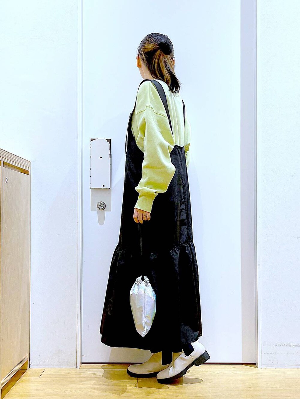 イエロー系のスウェット、ベージュ系のブーツ、その他のショルダーバッグを着用したレディースの冬コーディネートの3枚目の写真