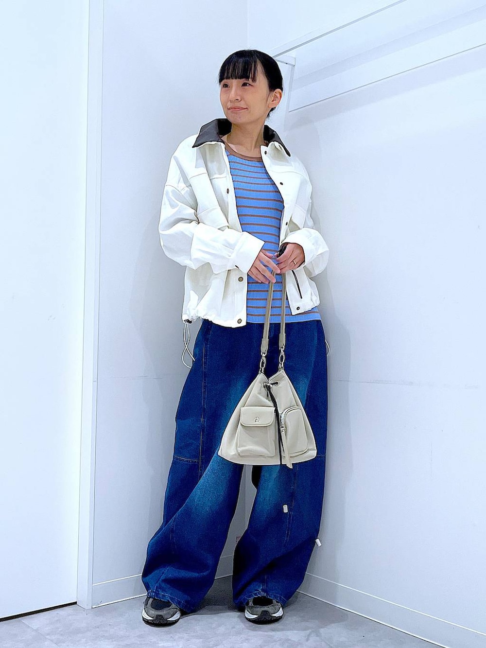 ブルー系のニット/セーター、ブルー系のデニムパンツ、ベージュ系のブルゾンを着用したレディースの冬コーディネートの2枚目の写真