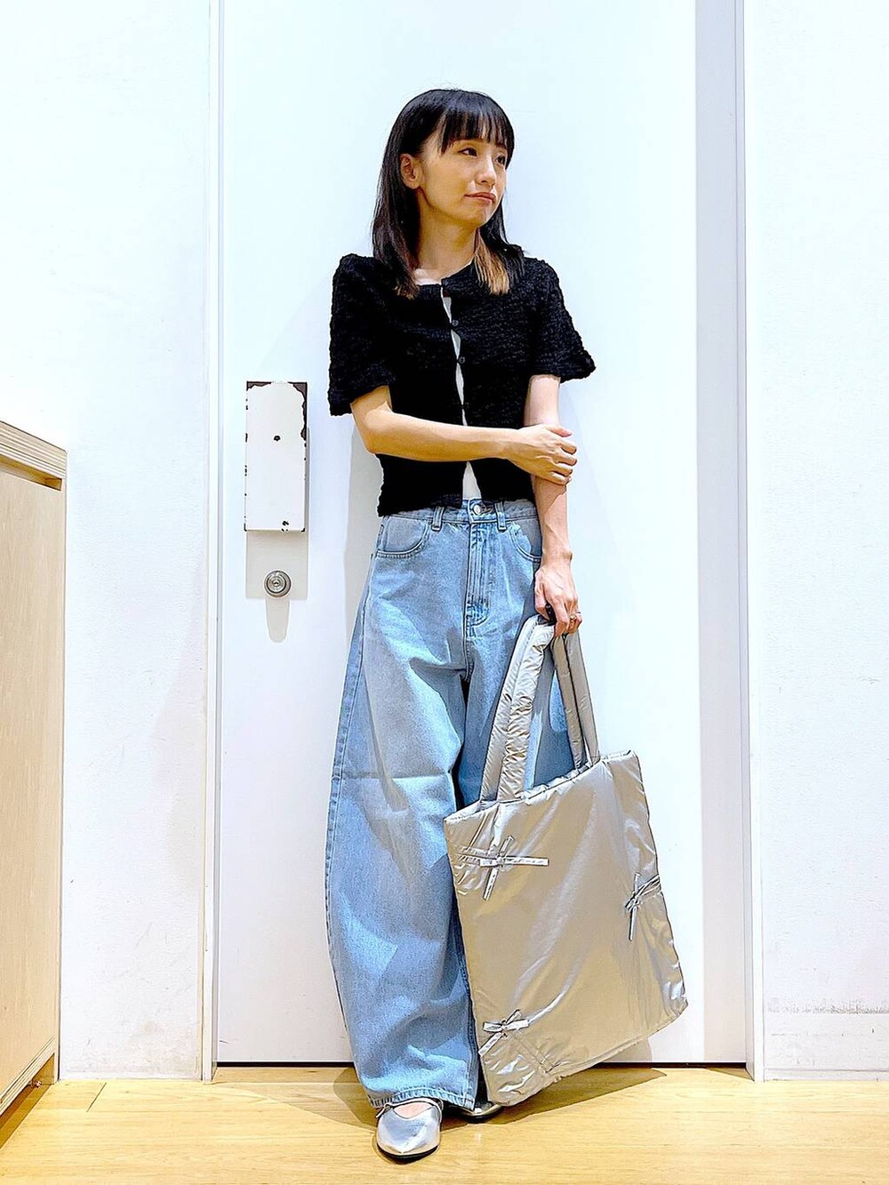 ブラック系のカーディガン/ボレロ、シルバー系のトートバッグ、ブルー系のデニムパンツを着用したレディースの秋コーディネートの2枚目の写真