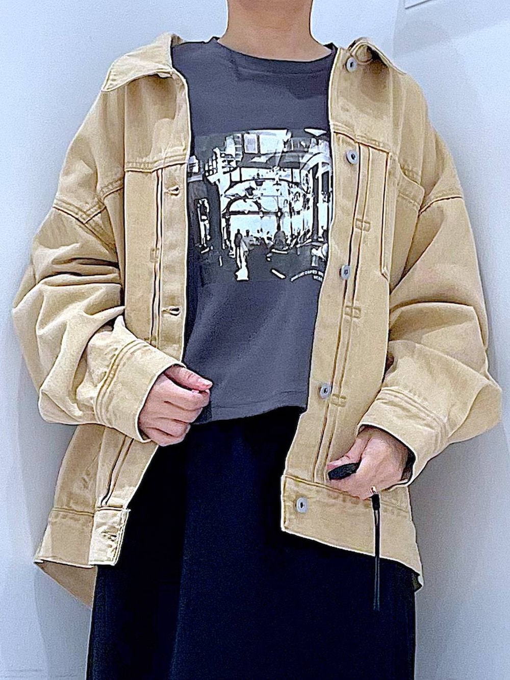 ブラック系のスカート、ベージュ系のデニムジャケット、ブラック系のショルダーバッグを着用したレディースの春コーディネートの7枚目の写真