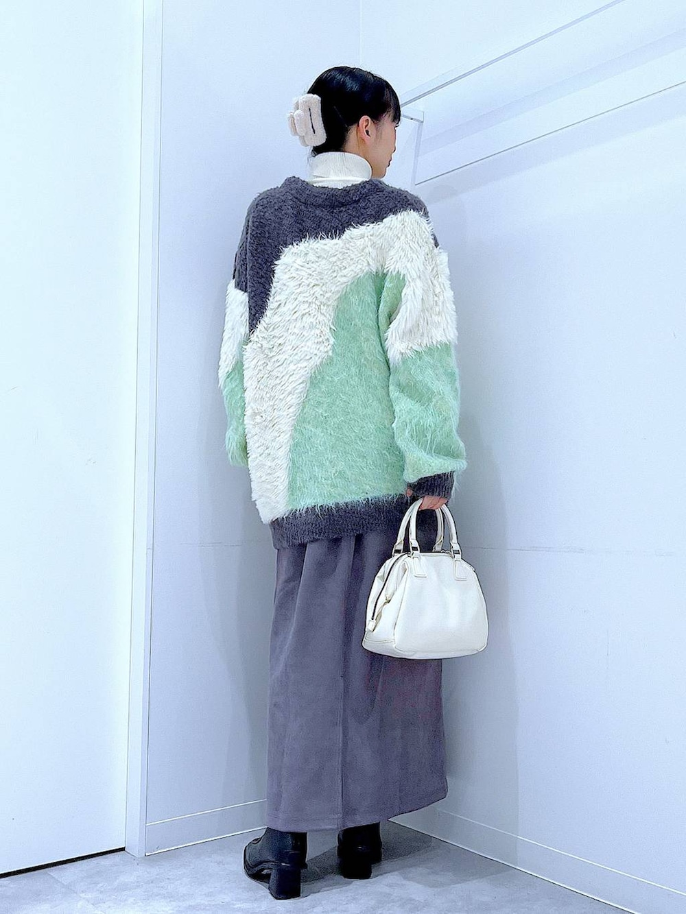 グリーン系のカーディガン/ボレロ、ブラック系のブーツ、ホワイト系のショルダーバッグを着用したレディースの冬コーディネートの5枚目の写真