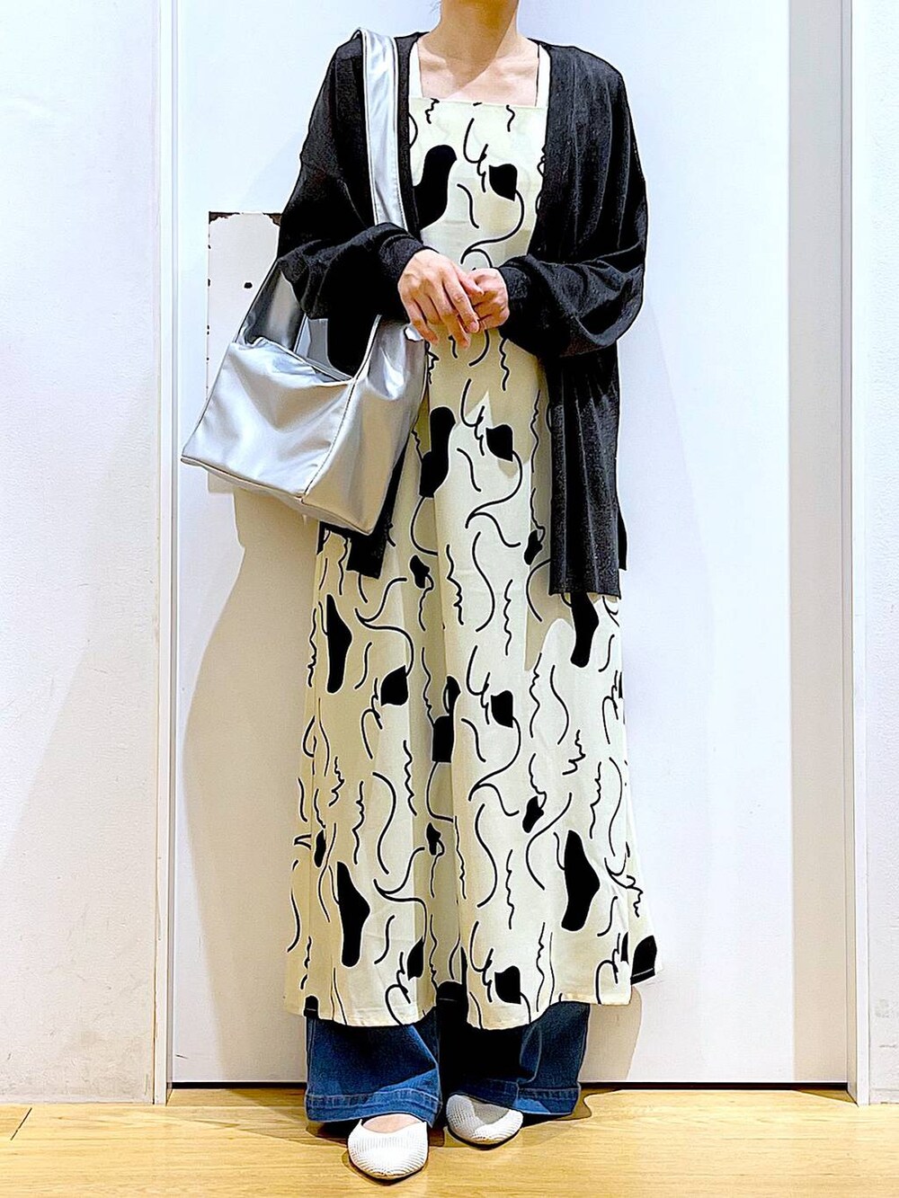 ブルー系のデニムパンツ、ベージュ系のワンピース、シルバー系のショルダーバッグを着用したレディースの春コーディネートの6枚目の写真