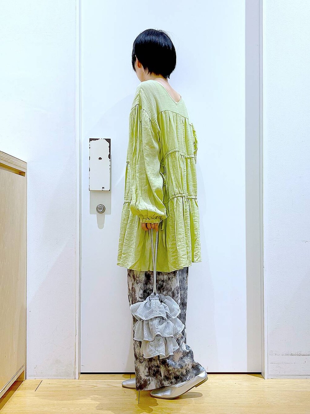 シルバー系のショルダーバッグ、シルバー系のパンプス、グリーン系のチュニックを着用したレディースの春コーディネートの3枚目の写真