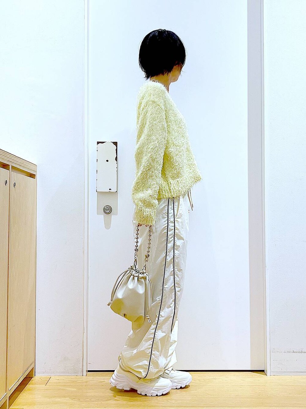 ベージュ系のショルダーバッグ、ホワイト系のスニーカー、イエロー系のカーディガン/ボレロを着用したレディースの秋コーディネートの4枚目の写真