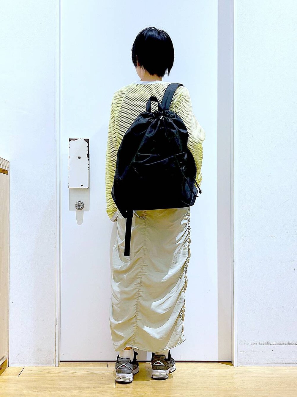 ベージュ系のスカート、ブラック系のバックパック/リュック、イエロー系のTシャツ/カットソーを着用したレディースの春コーディネートの5枚目の写真