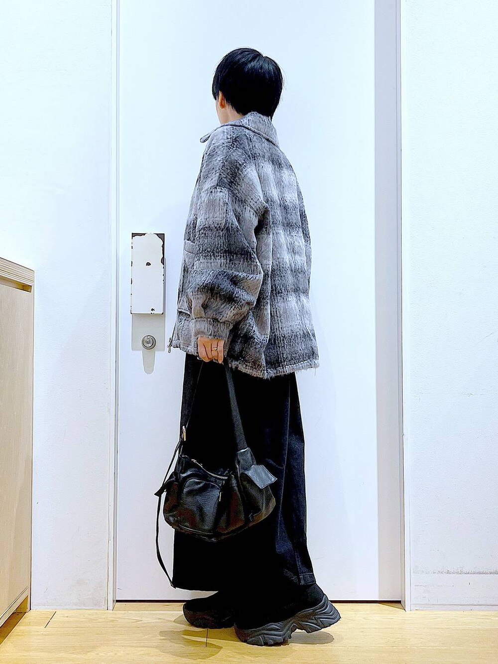 グレー系のジャンパースカート、ブラック系のブーツ、ブラック系のショルダーバッグを着用したレディースの冬コーディネートの3枚目の写真