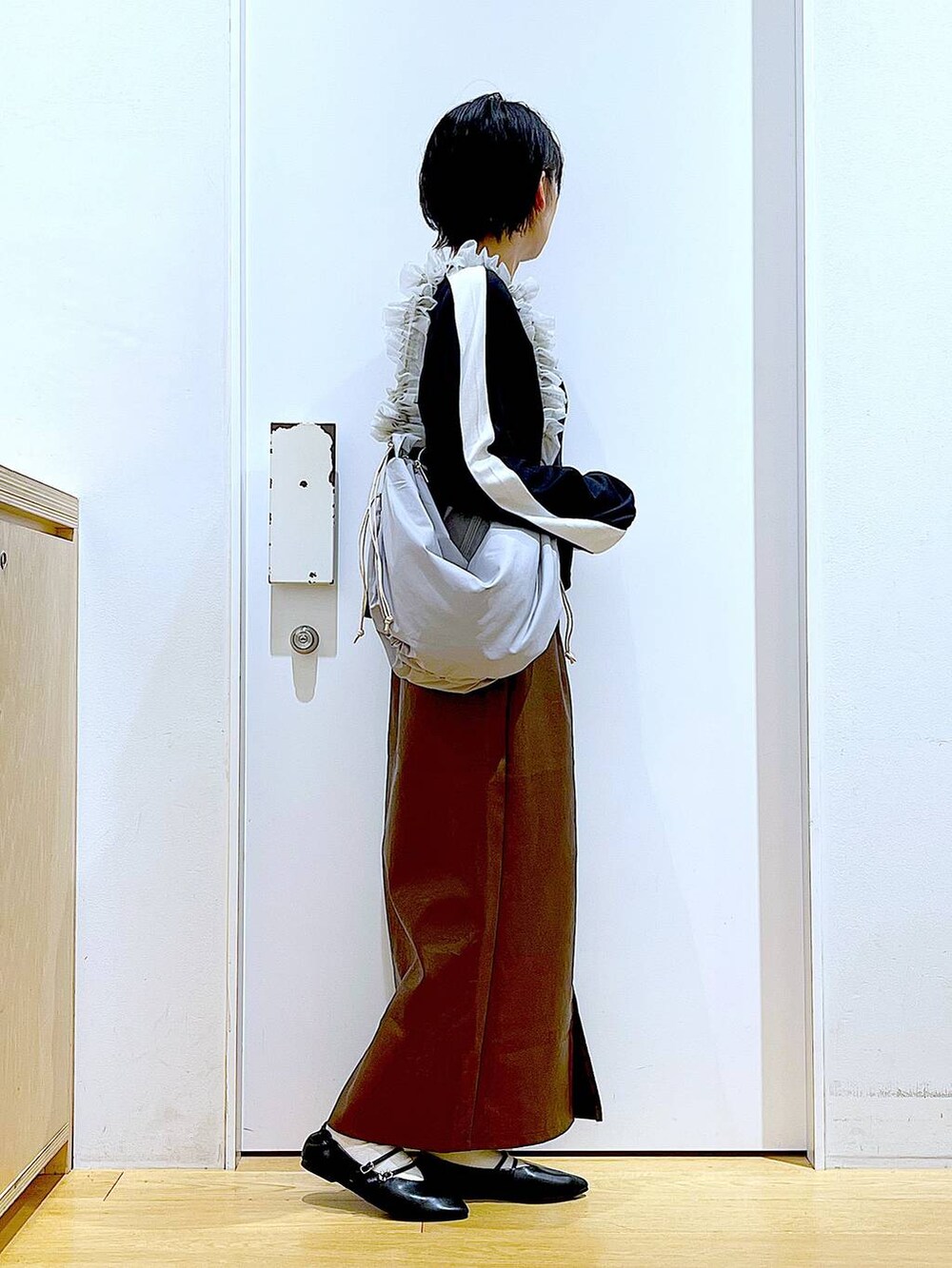 ブラウン系のスカート、ブラック系のパンプス、グレー系のショルダーバッグを着用したレディースの秋コーディネートの4枚目の写真