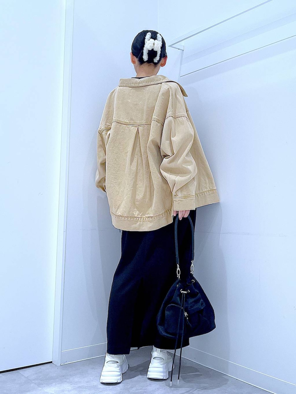 ブラック系のスカート、ベージュ系のデニムジャケット、ブラック系のショルダーバッグを着用したレディースの春コーディネートの5枚目の写真