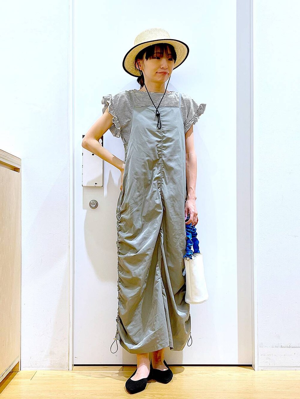 ブルー系のショルダーバッグ、ブラック系のパンプス、グリーン系のワンピースを着用したレディースの春コーディネートの2枚目の写真