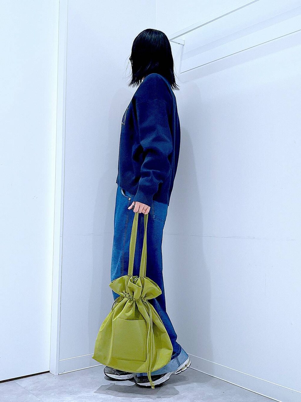 グリーン系のトートバッグ、ブルー系のニット/セーター、ブルー系のデニムパンツを着用したレディースの冬コーディネートの3枚目の写真