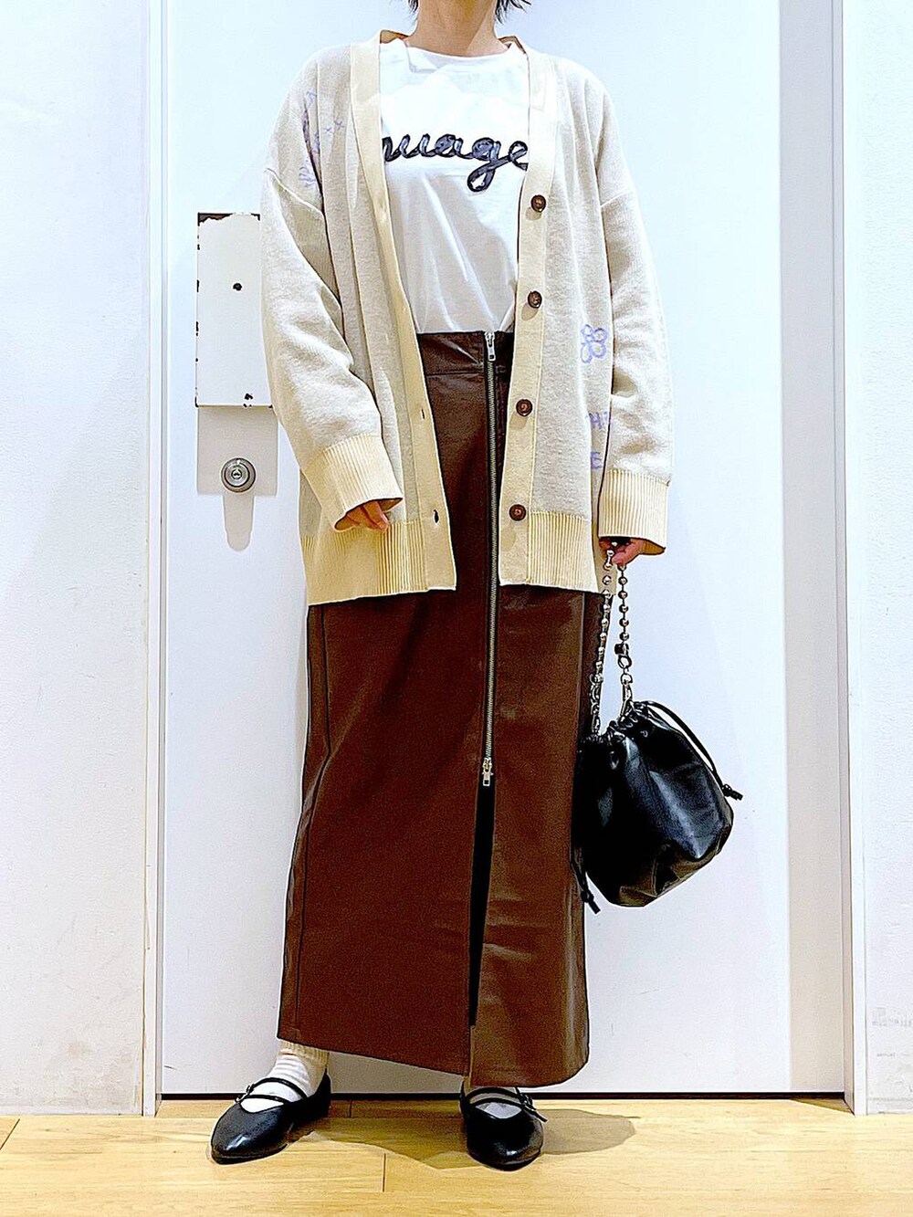 ブラウン系のスカート、ブラック系のショルダーバッグ、ブラック系のパンプスを着用したレディースの秋コーディネートの6枚目の写真