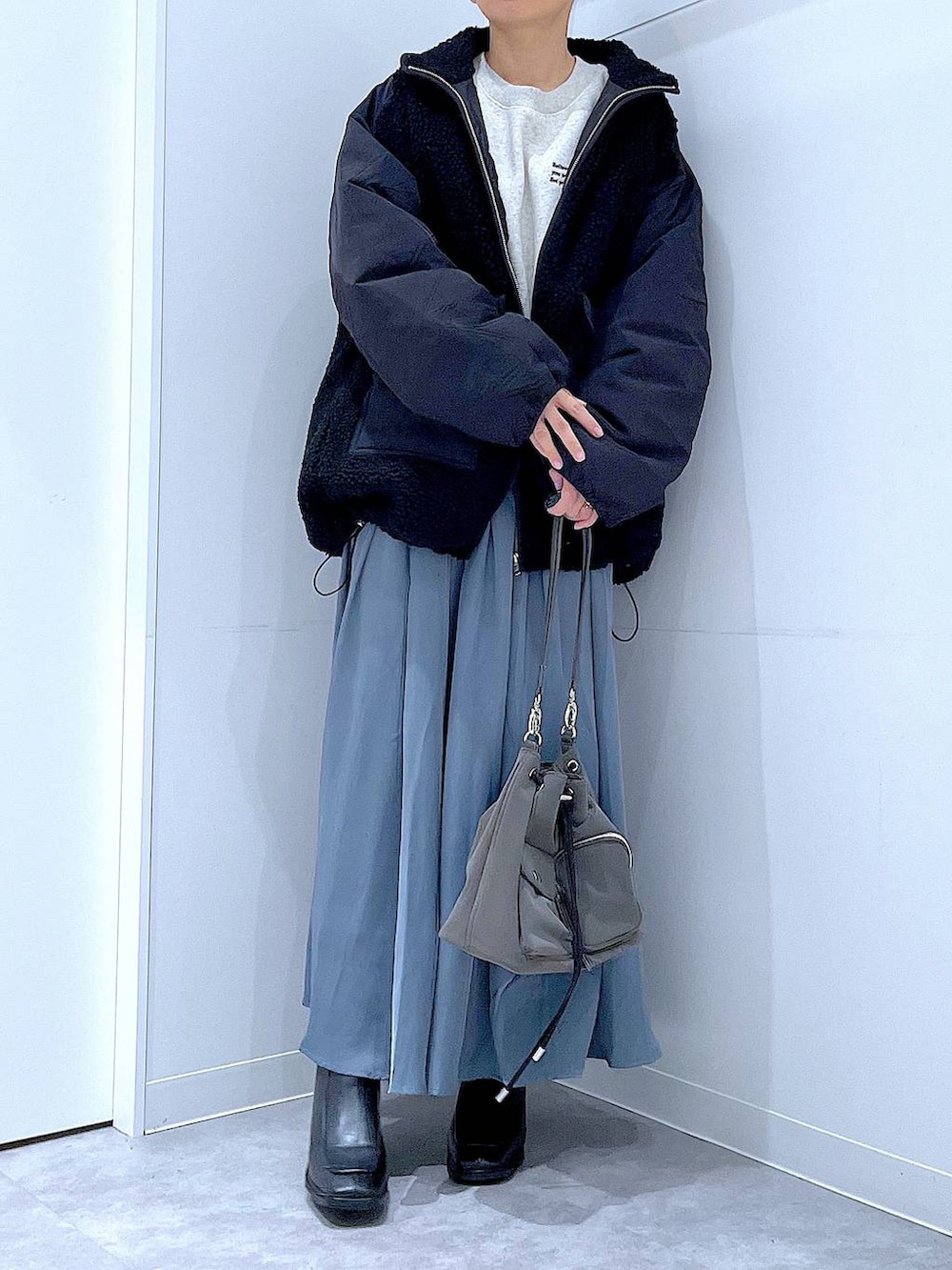 ブラック系のブルゾン、ブラック系のブーツ、ブルー系のスカートを着用したレディースの冬コーディネートの6枚目の写真