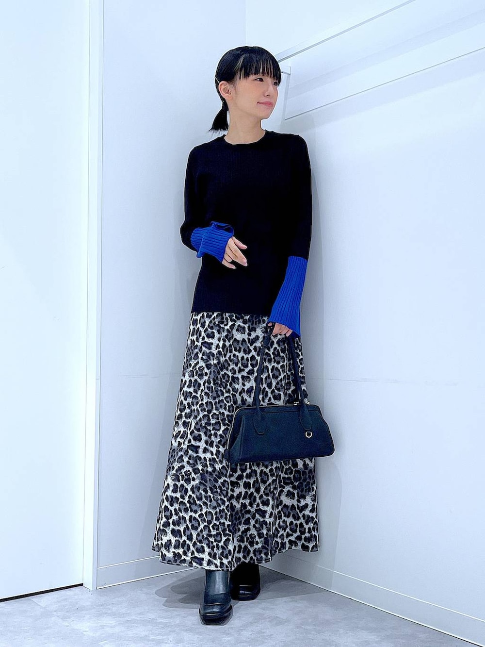 ブラック系のニット/セーター、ブラック系のブーツ、グレー系のスカートを着用したレディースの秋コーディネートの2枚目の写真