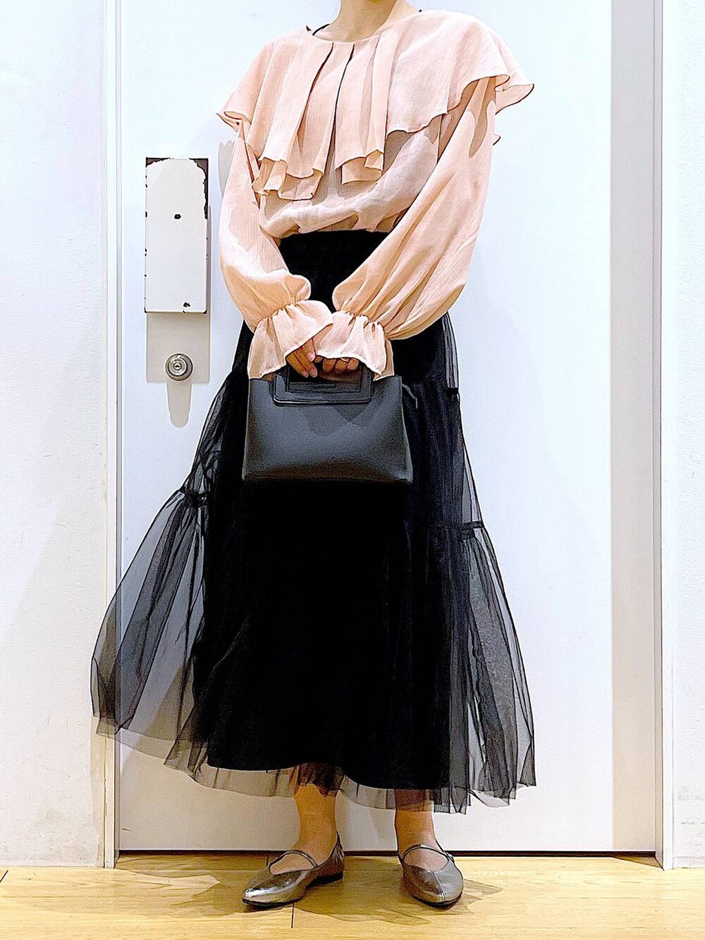 ブラック系のスカート、ブラック系のショルダーバッグ、その他のパンプスを着用したレディースの春コーディネートの6枚目の写真