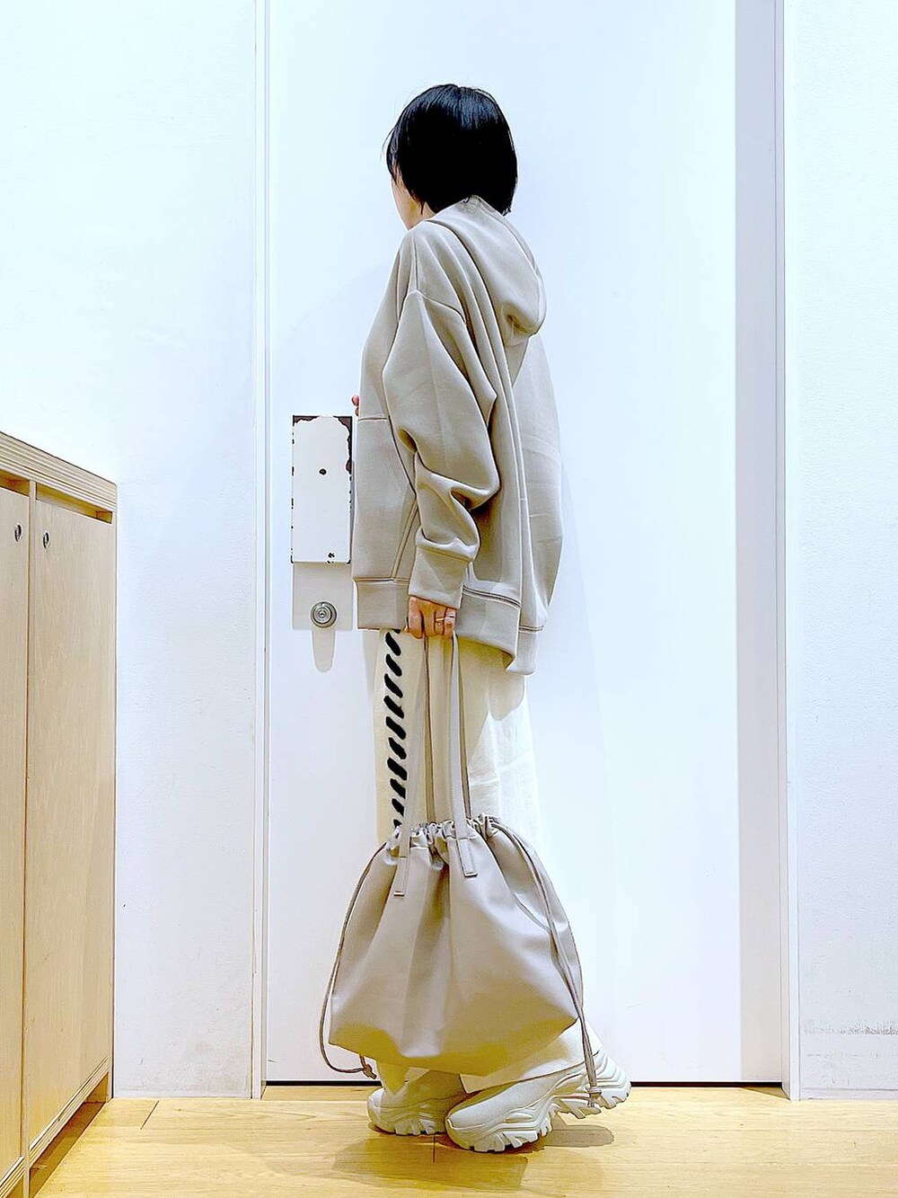 ベージュ系のトートバッグ、ベージュ系のブーツ、ベージュ系のスカートを着用したレディースの秋コーディネートの3枚目の写真