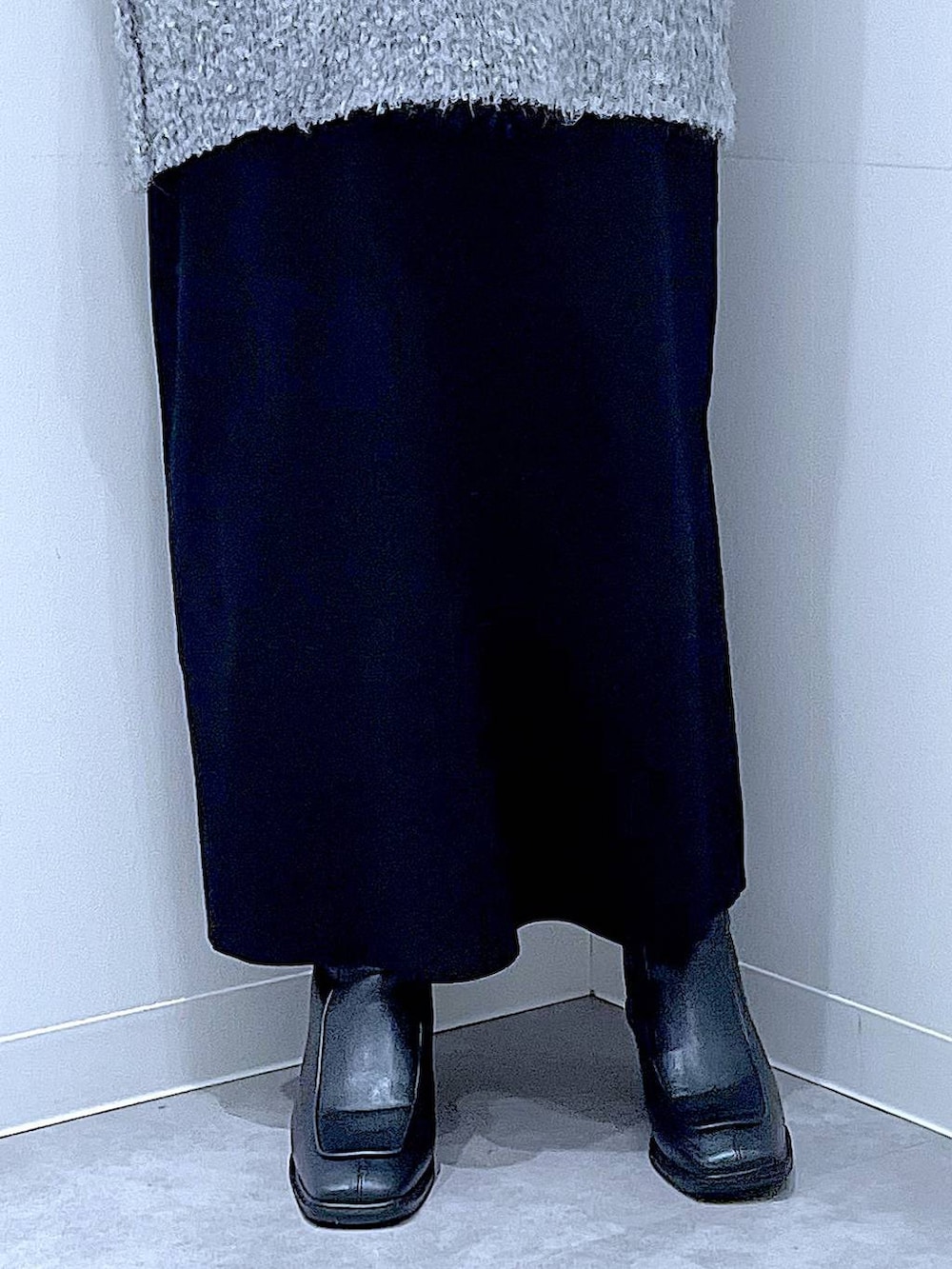 ブラック系のブーツ、グレー系のニット/セーター、ブラック系のスカートを着用したレディースの冬コーディネートの8枚目の写真