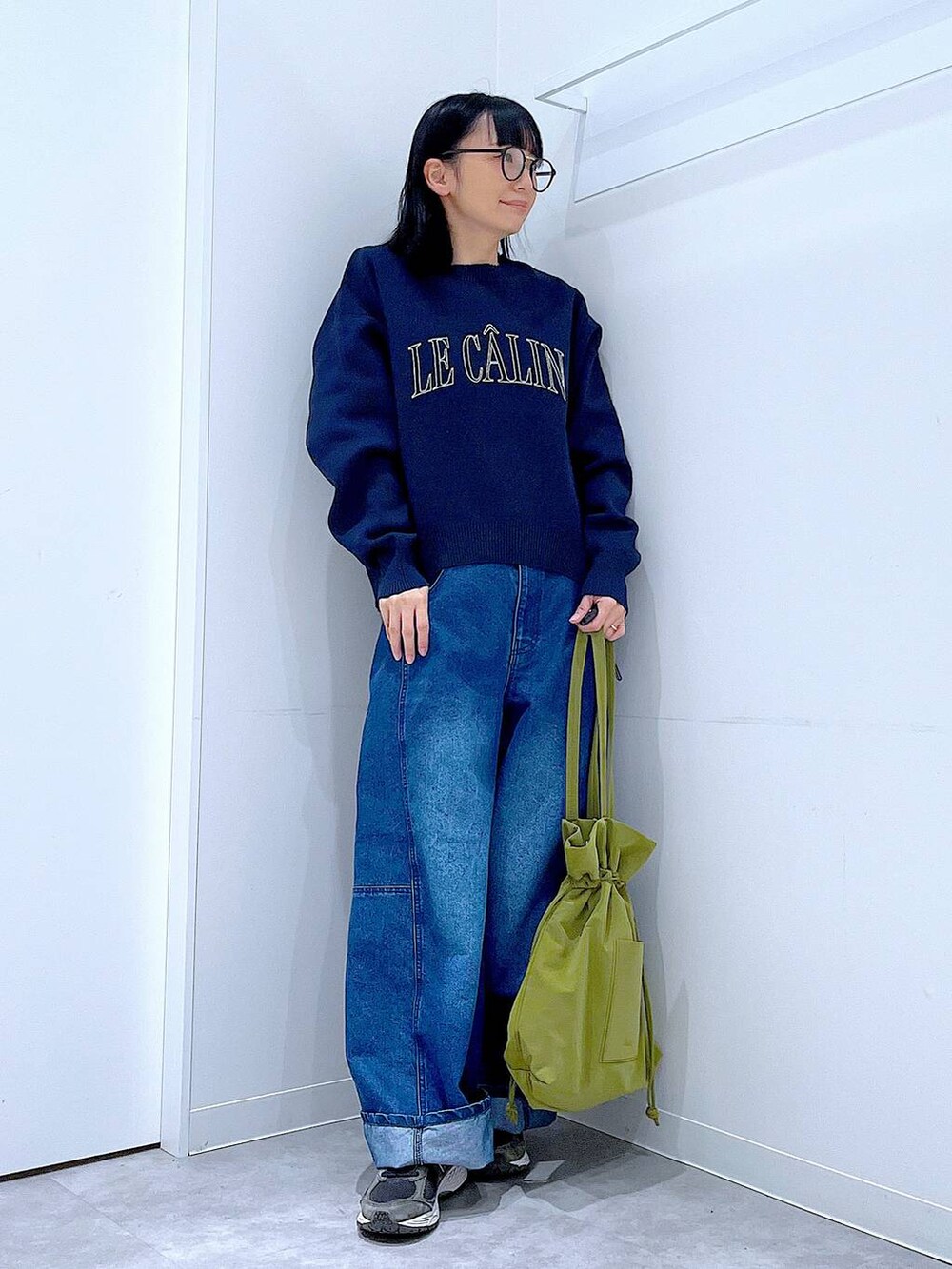 グリーン系のトートバッグ、ブルー系のニット/セーター、ブルー系のデニムパンツを着用したレディースの冬コーディネートの2枚目の写真