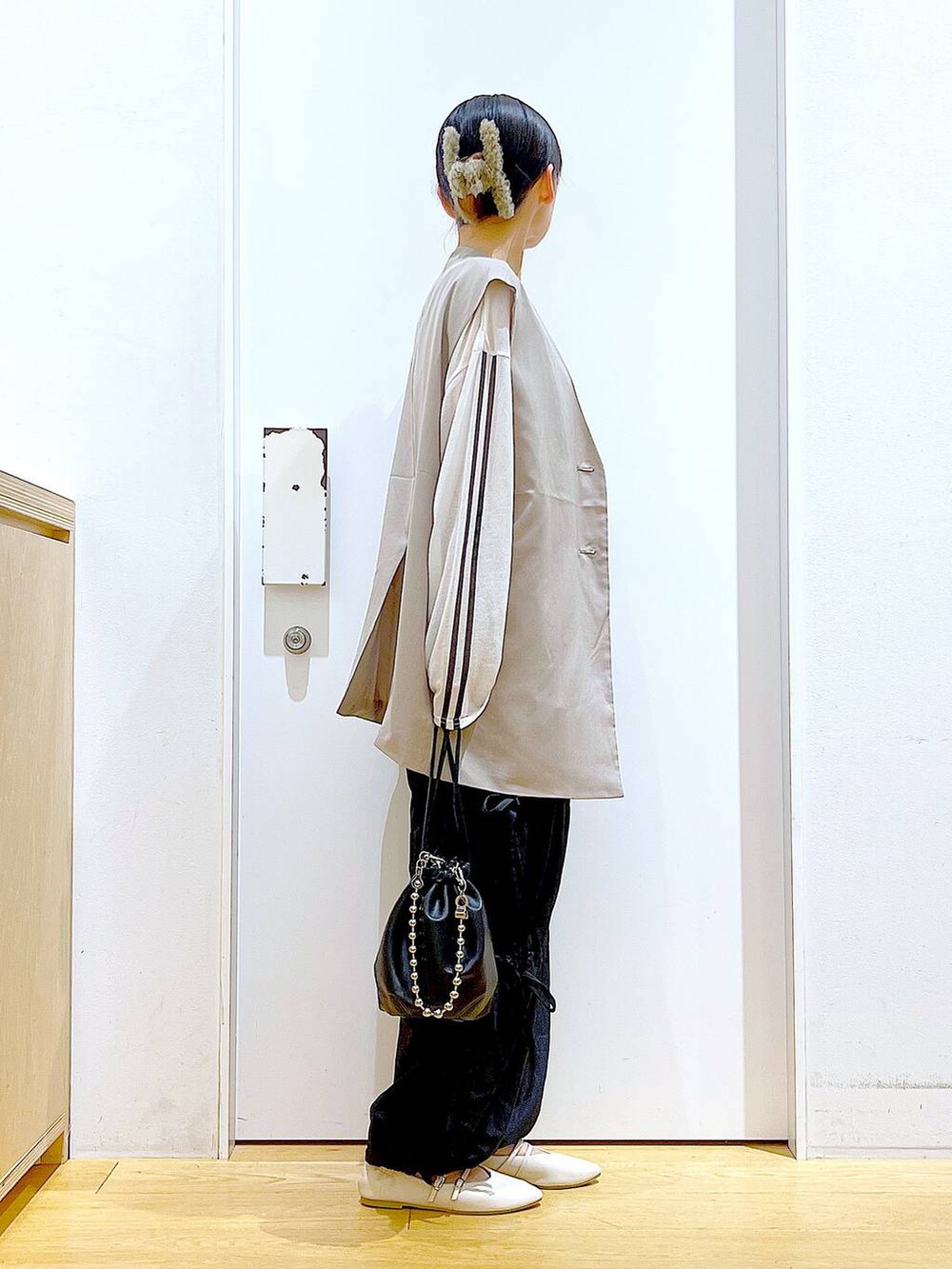 ブラック系のショルダーバッグ、ホワイト系のパンプス、ブラック系のその他パンツを着用したレディースの秋コーディネートの4枚目の写真