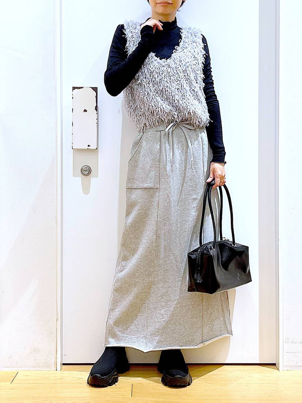 ブラック系のブーツ、ブラック系のTシャツ/カットソー、グレー系のスカートを着用したレディースの春コーディネートの6枚目の写真