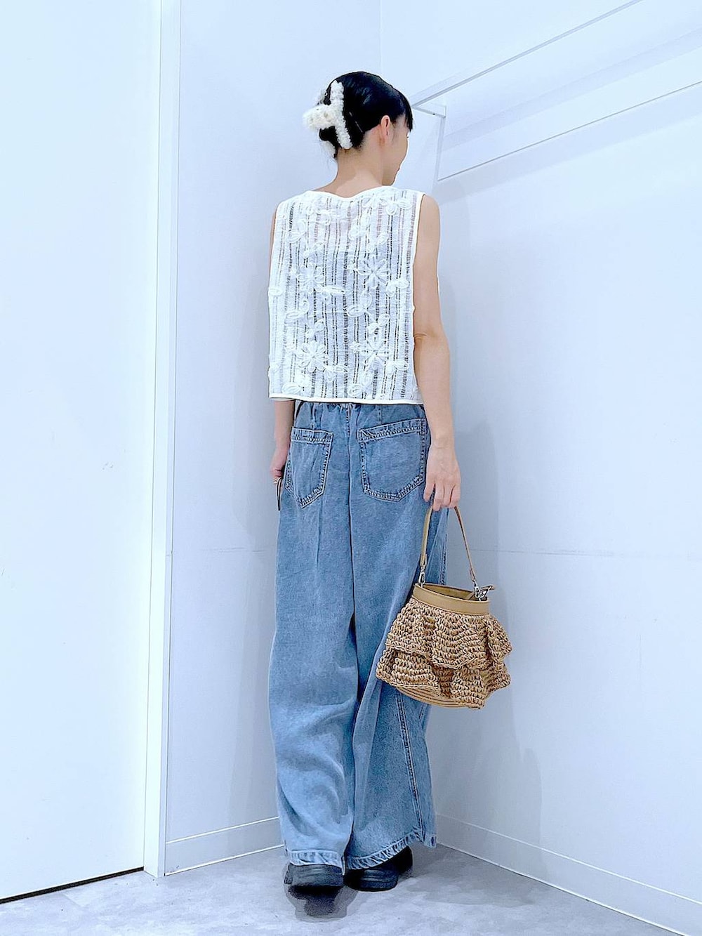ベージュ系のショルダーバッグ、ブルー系のデニムパンツ、ベージュ系のベストを着用したレディースの夏コーディネートの5枚目の写真