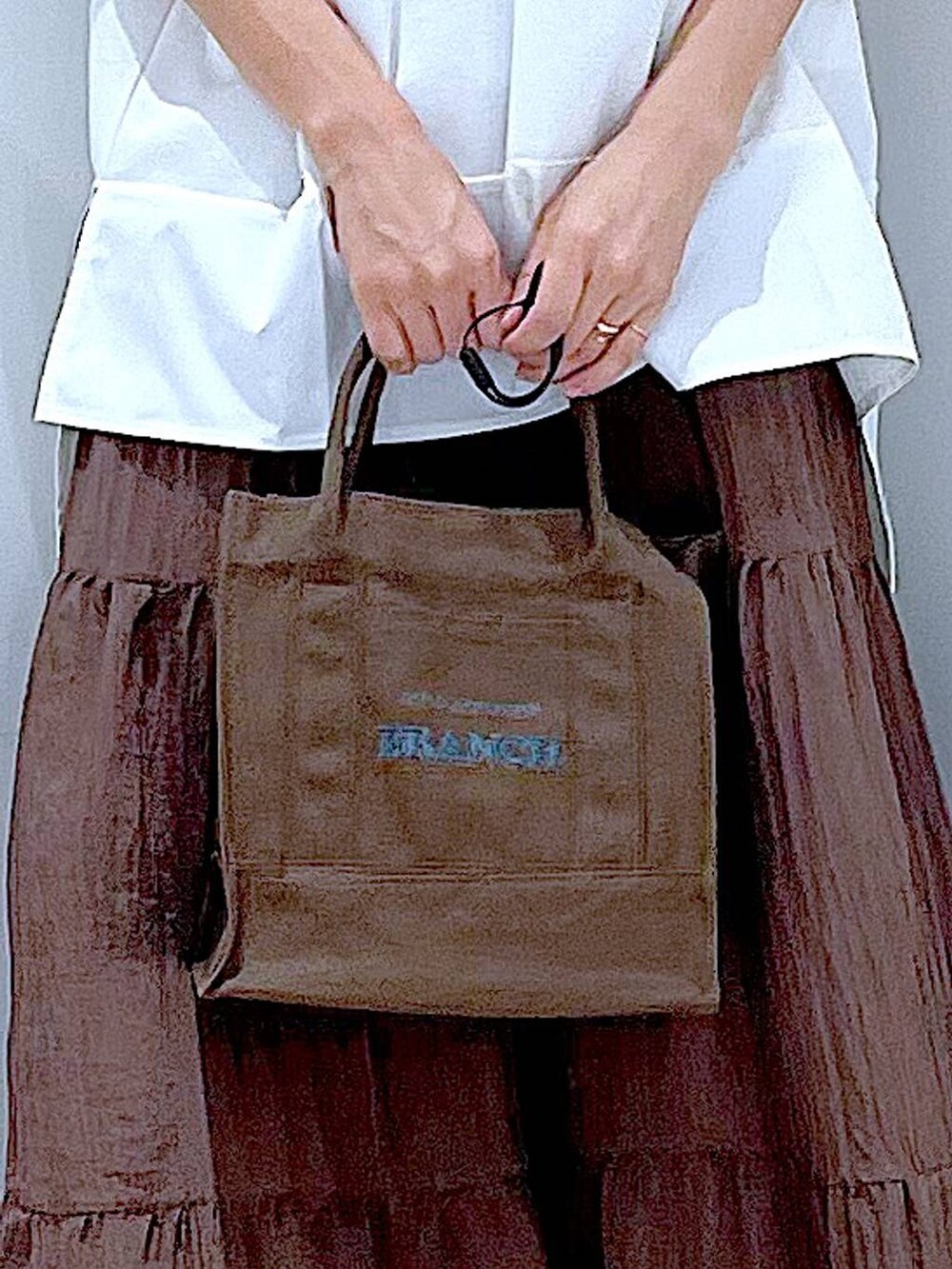 ホワイト系のサンダル、ホワイト系のTシャツ/カットソー、ブラウン系のスカートを着用したレディースの夏コーディネートの7枚目の写真