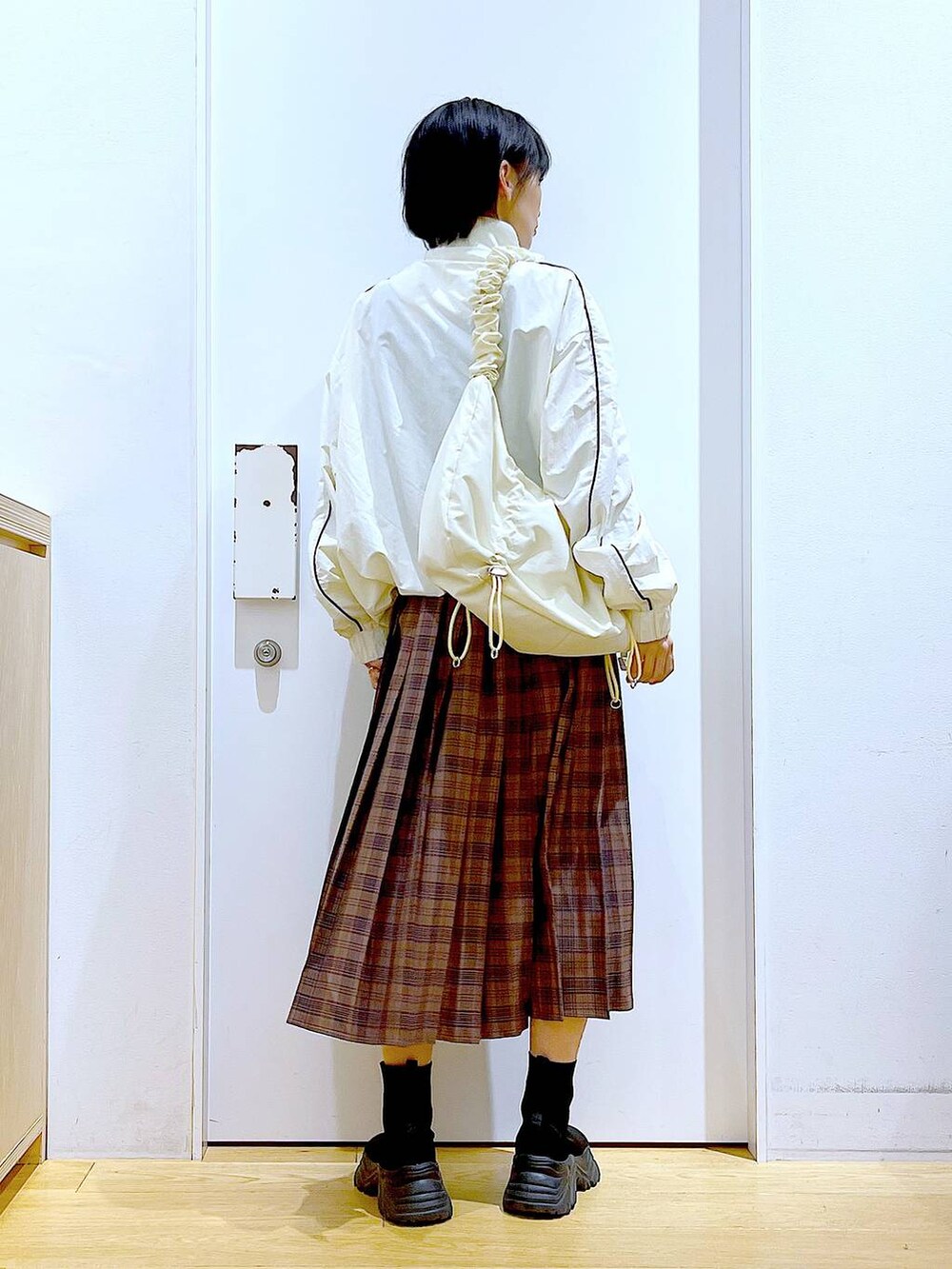 ホワイト系のショルダーバッグ、ベージュ系のブルゾン、ブラック系のブーツを着用したレディースの秋コーディネートの5枚目の写真