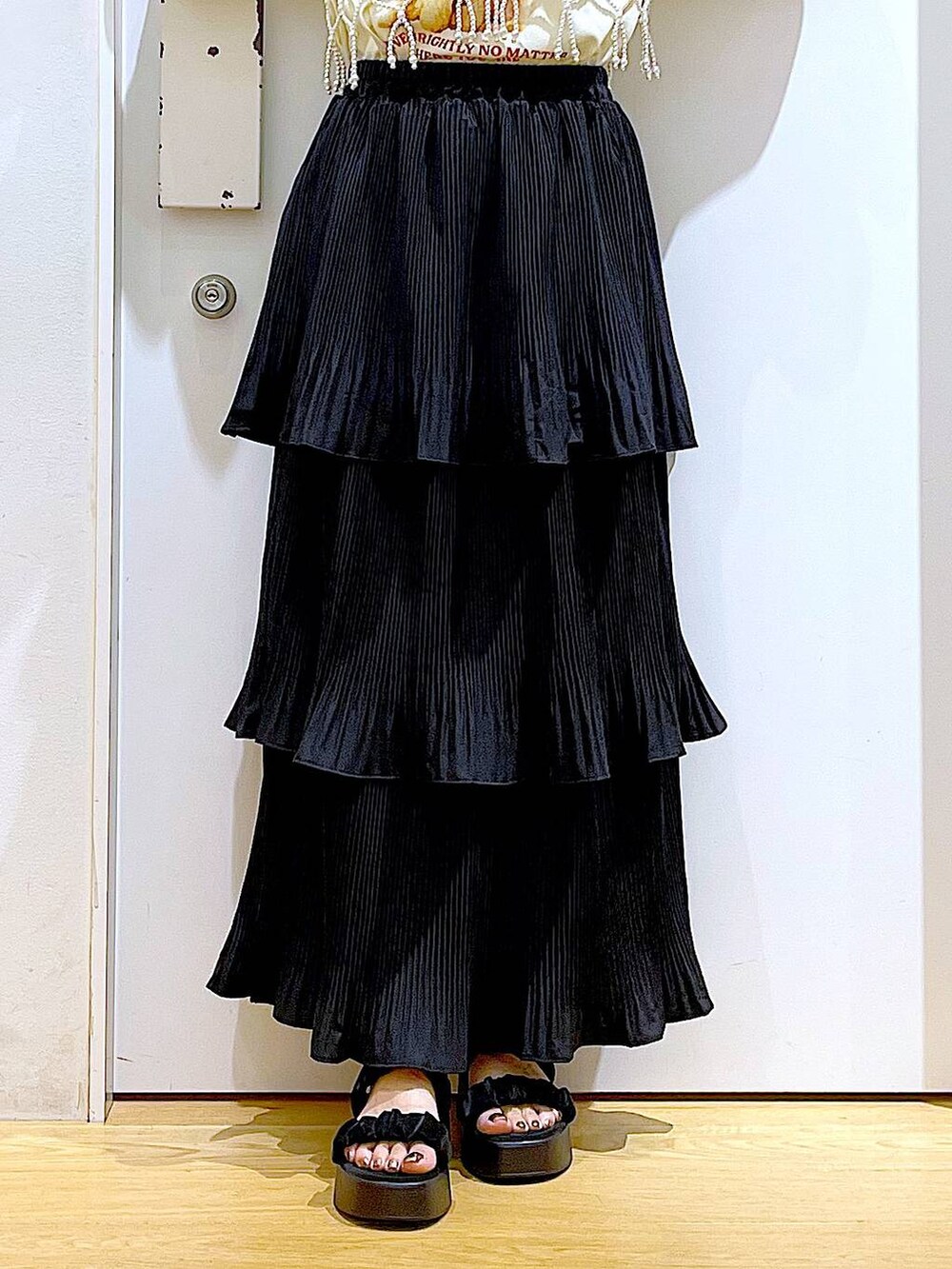 ブラック系のスカート、ブラック系のサンダル、ホワイト系のベストを着用したレディースの秋コーディネートの8枚目の写真