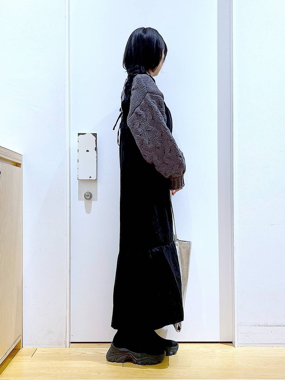 シルバー系のトートバッグ、ブラック系のブーツ、グレー系のニット/セーターを着用したレディースの冬コーディネートの4枚目の写真