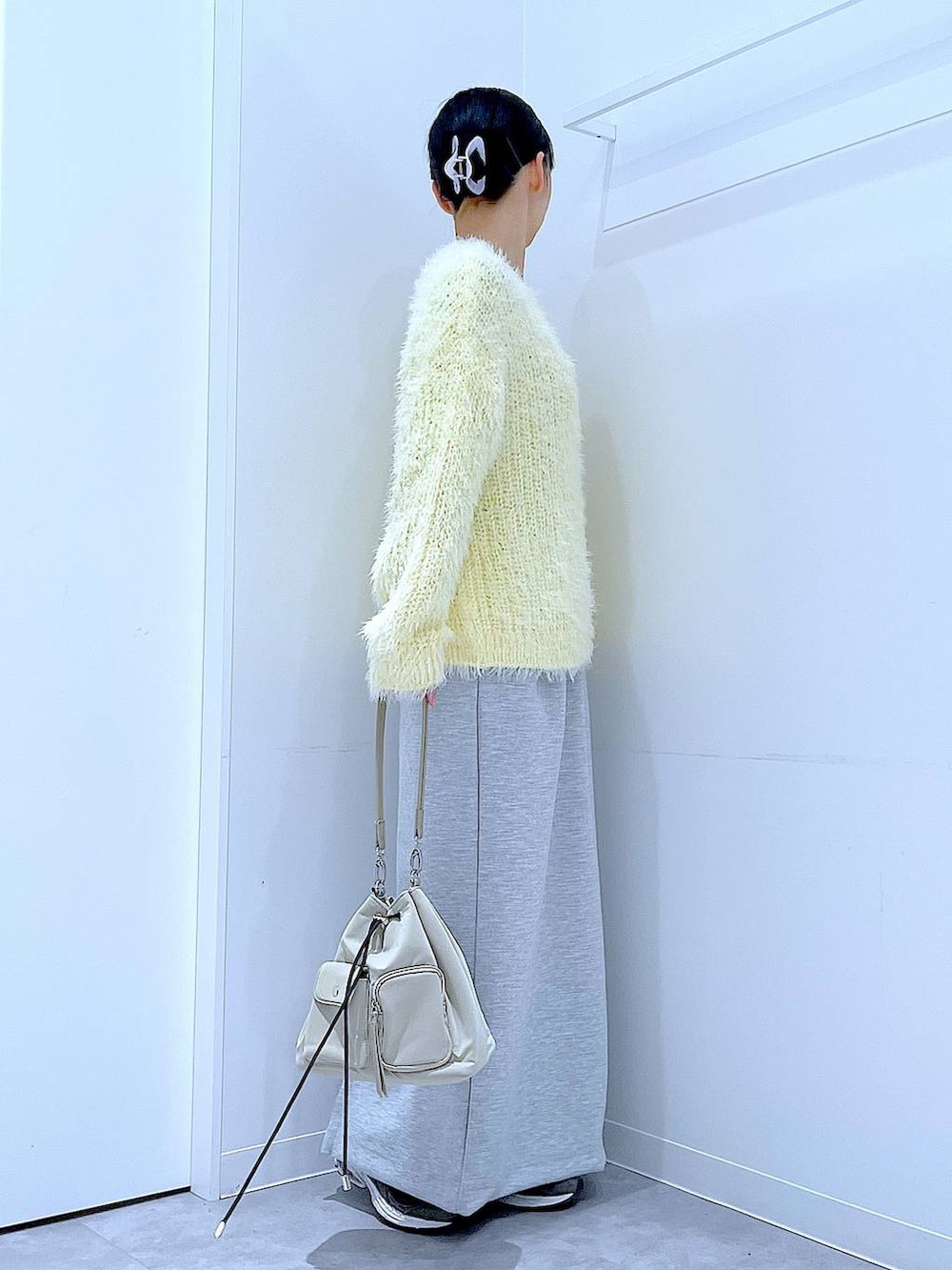 イエロー系のニット/セーター、グレー系のスカート、パープル系のバレッタ/ヘアクリップを着用したレディースの冬コーディネートの4枚目の写真