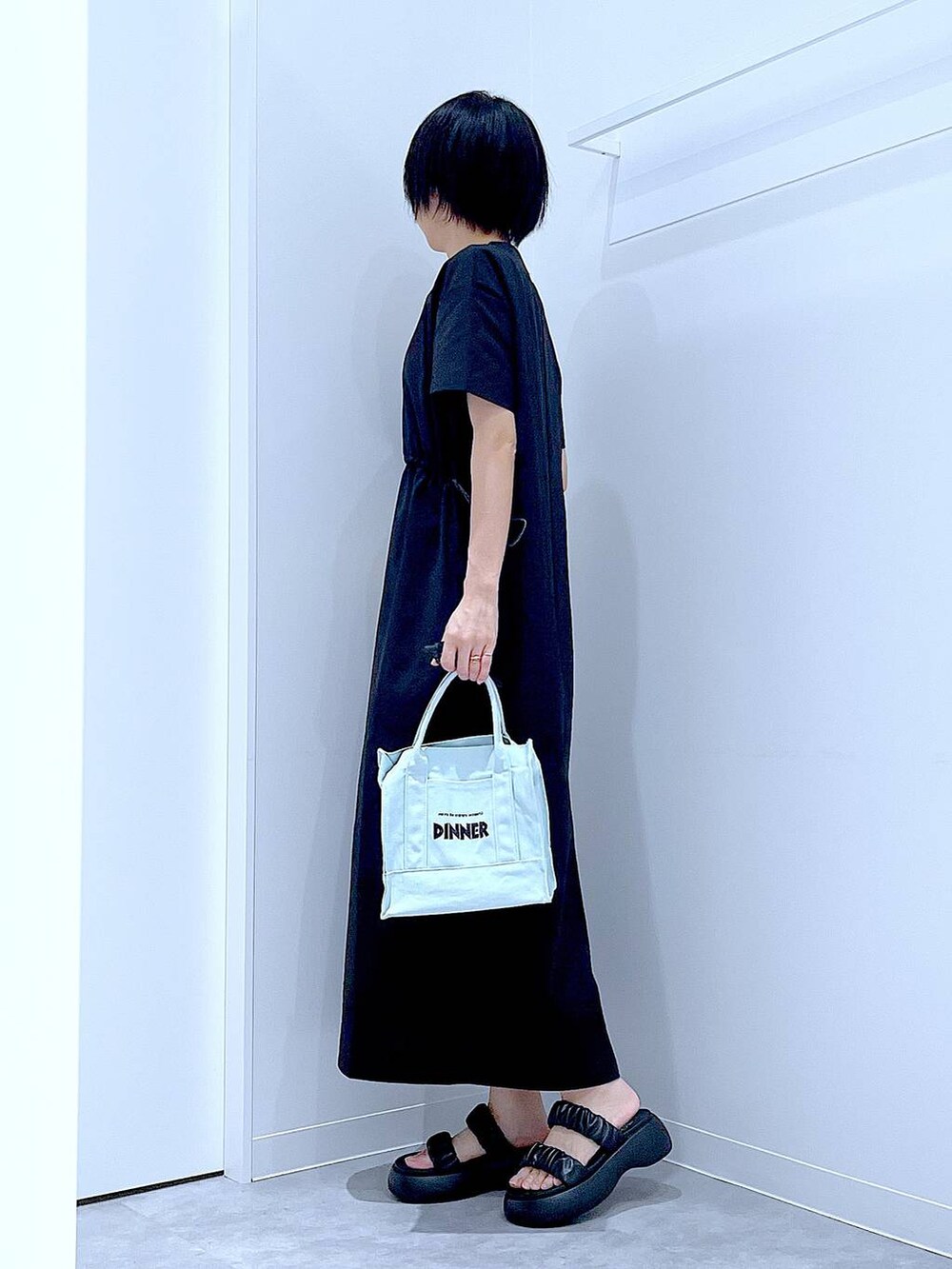 ブラック系のサンダル、ブラック系のワンピース、グリーン系のトートバッグを着用したレディースの夏コーディネートの3枚目の写真