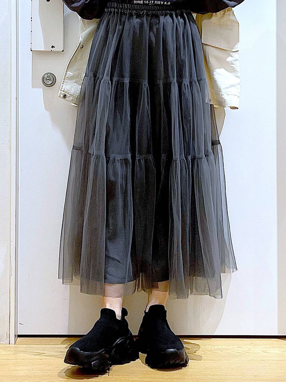 グレー系のスカート、ブラック系のスニーカー、ホワイト系のベストを着用したレディースの春コーディネートの8枚目の写真