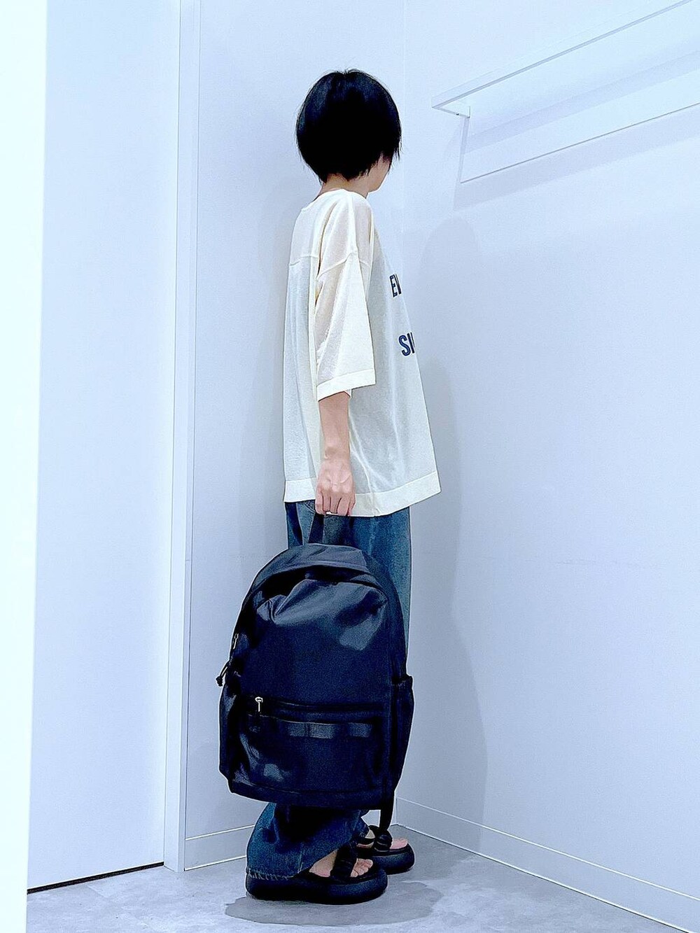 ブルー系のデニムパンツ、ブラック系のバックパック/リュック、ブラック系のサンダルを着用したレディースの夏コーディネートの4枚目の写真