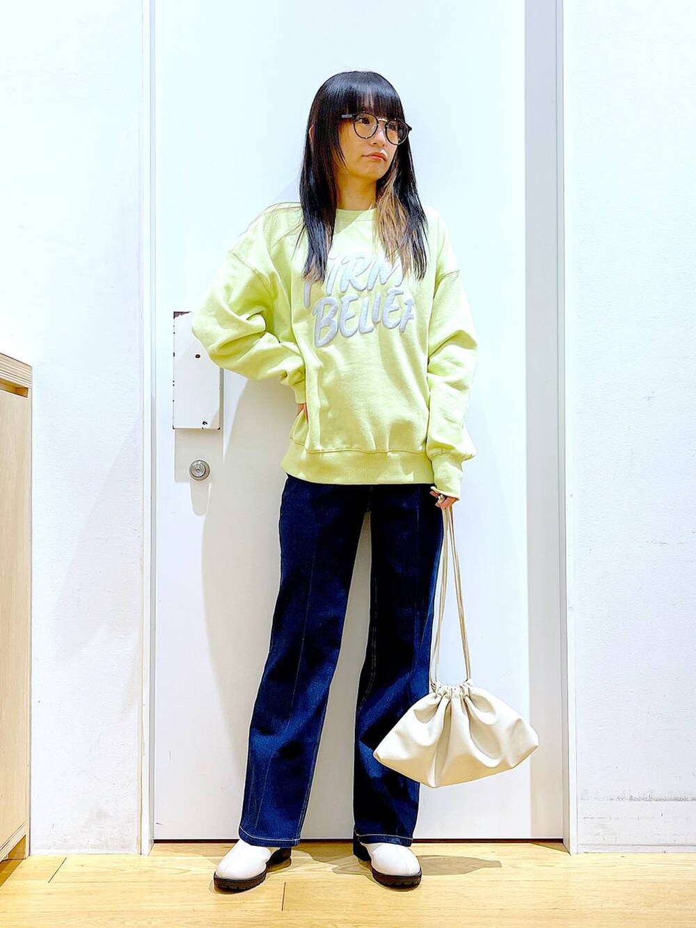 ブルー系のデニムパンツ、イエロー系のスウェット、ベージュ系のブーツを着用したレディースの冬コーディネートの2枚目の写真