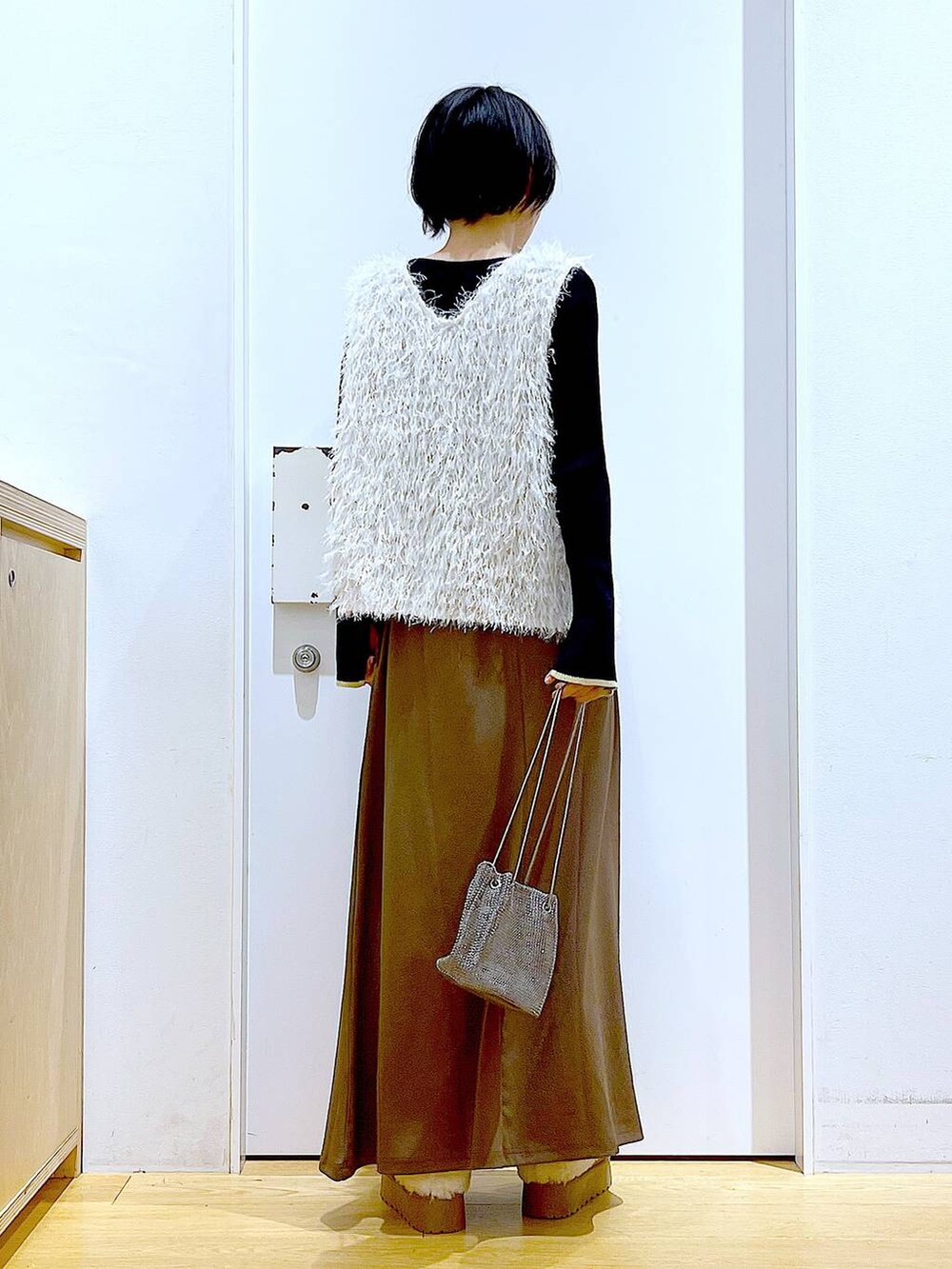 ブラック系のニット/セーター、グレー系のショルダーバッグ、ベージュ系のベストを着用したレディースの秋コーディネートの5枚目の写真