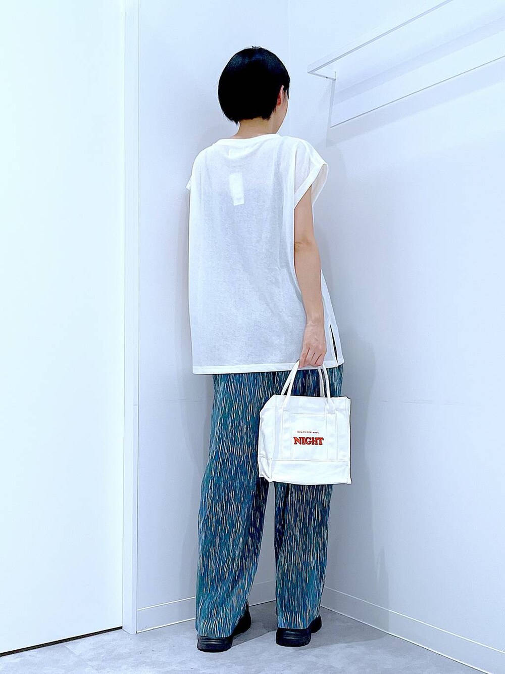 ブラック系のスニーカー、ホワイト系のTシャツ/カットソー、ホワイト系のトートバッグを着用したレディースの夏コーディネートの5枚目の写真