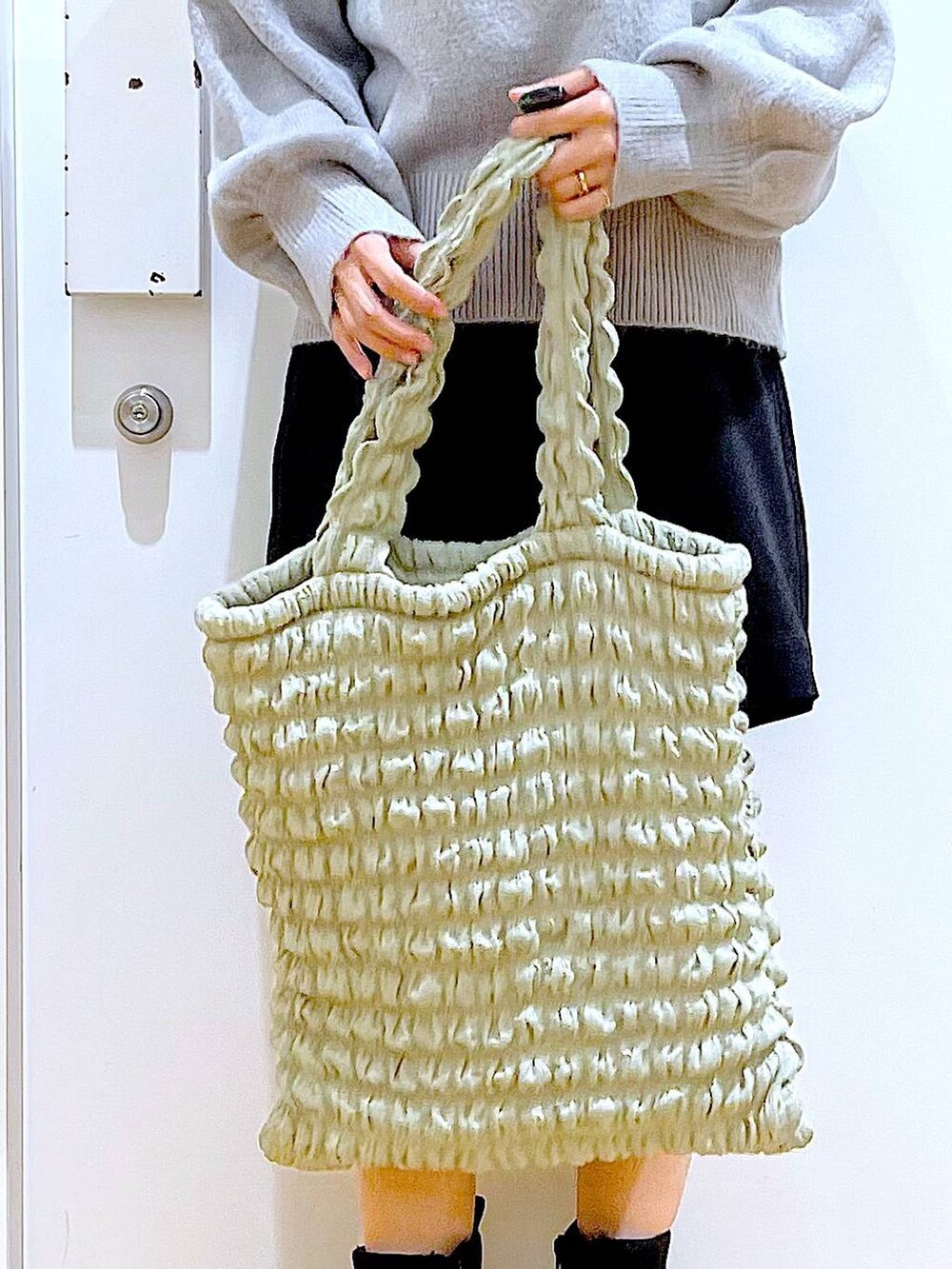 グリーン系のトートバッグ、ブラック系のブーツ、ブラック系のその他パンツを着用したレディースの冬コーディネートの9枚目の写真