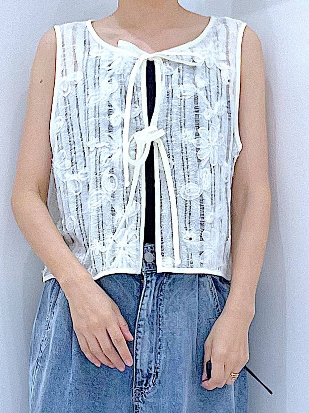 ベージュ系のショルダーバッグ、ブルー系のデニムパンツ、ベージュ系のベストを着用したレディースの夏コーディネートの7枚目の写真