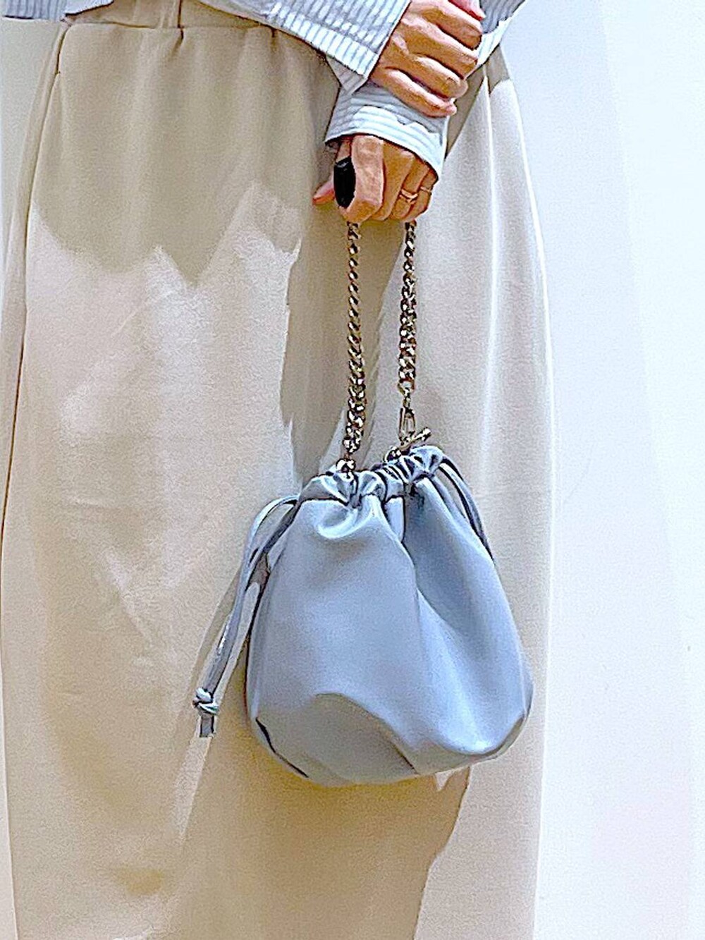 ブルー系のショルダーバッグ、ホワイト系のパンプス、ベージュ系のスカートを着用したレディースの春コーディネートの9枚目の写真